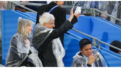 Cerimonia inaugurazione Olimpiadi, Mattarella in tribuna autorità sotto la pioggia si infila l'impermeabile