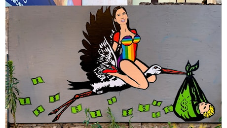 Elly Schlein cavalca una cicogna in versione arcobaleno: il murale sulla maternità surrogata spuntato a Milano nel giorno del Pride – Foto e video
